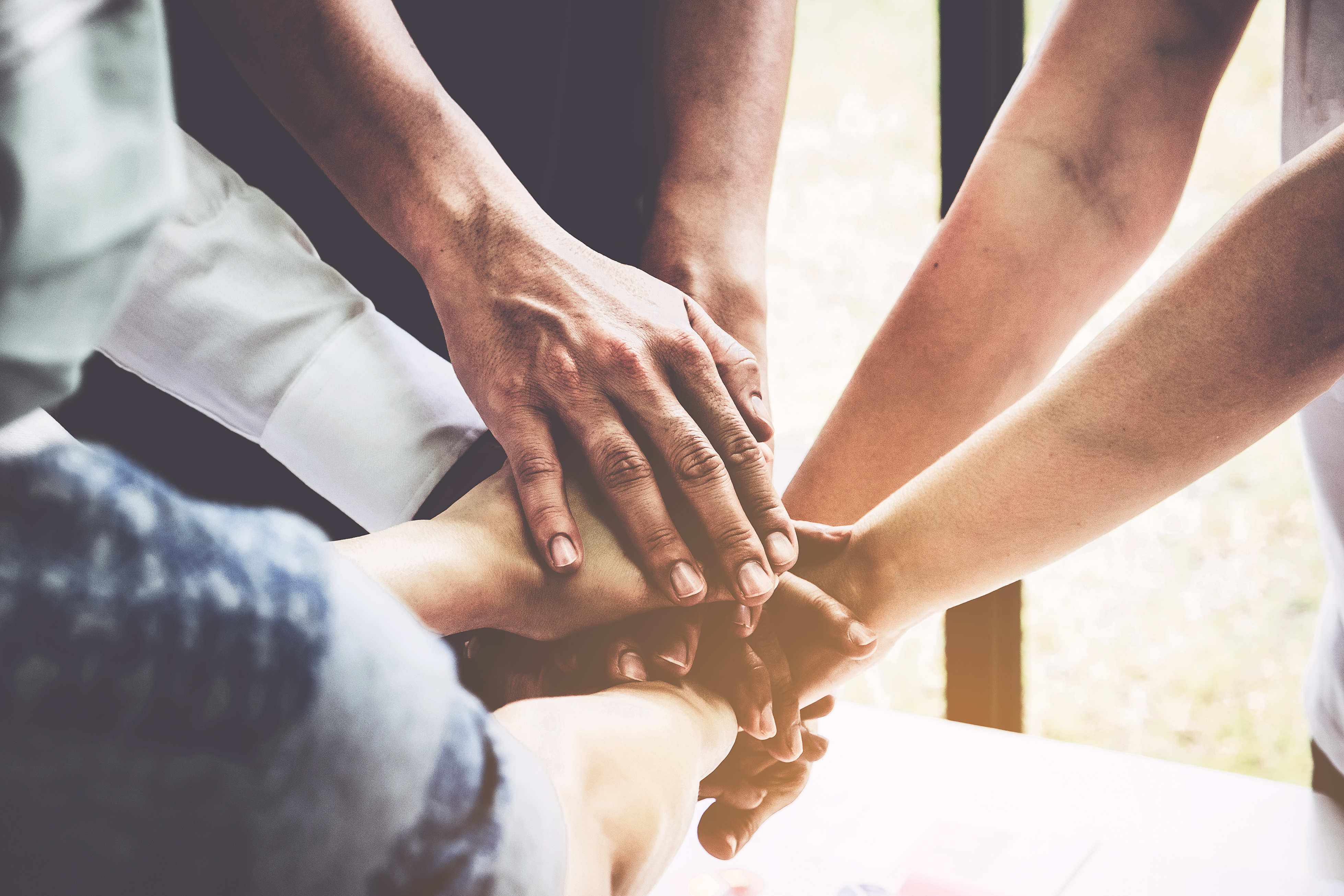 group-of-business-people-putting-their-hands-working-together-on-wooden